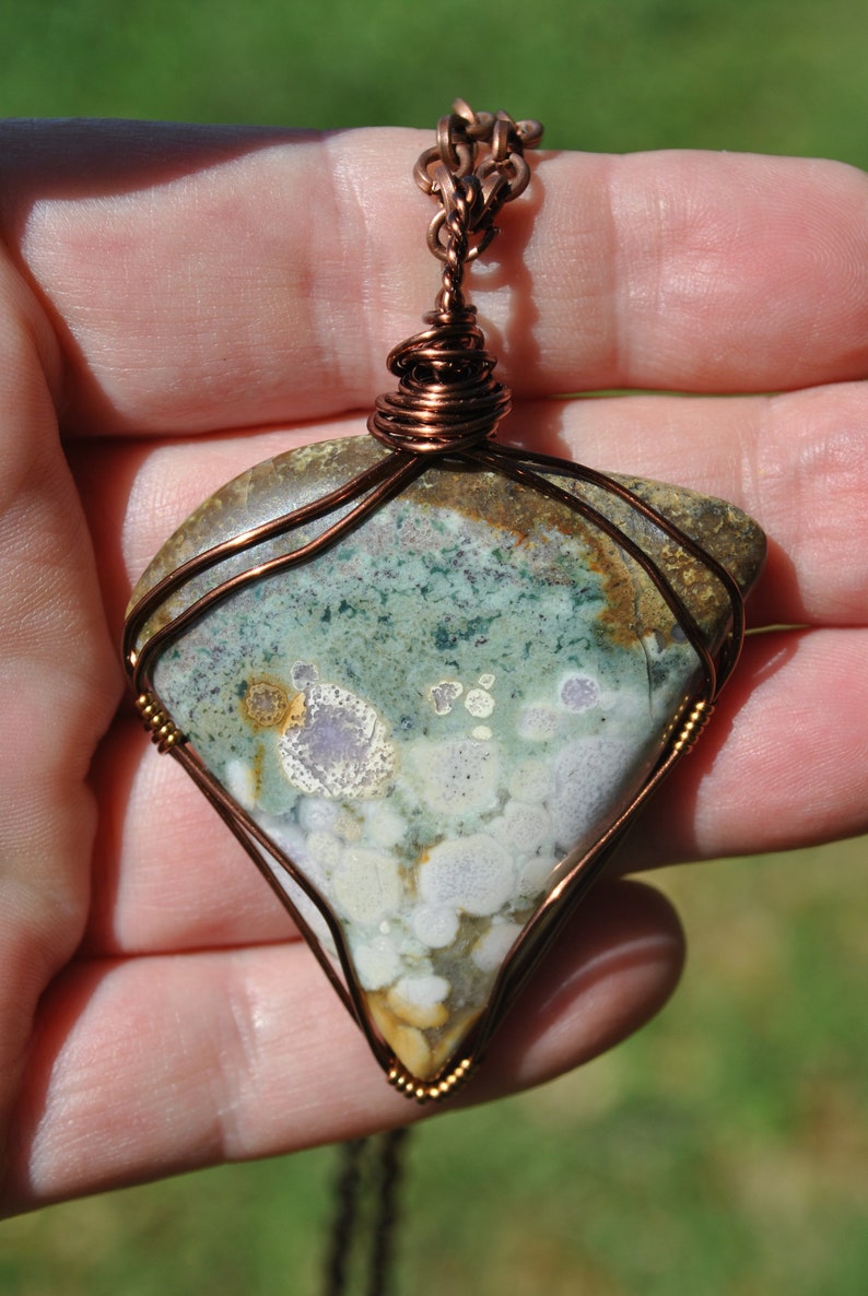 May include: A copper wire wrapped pendant featuring a green, white and brown agate stone with a copper chain.