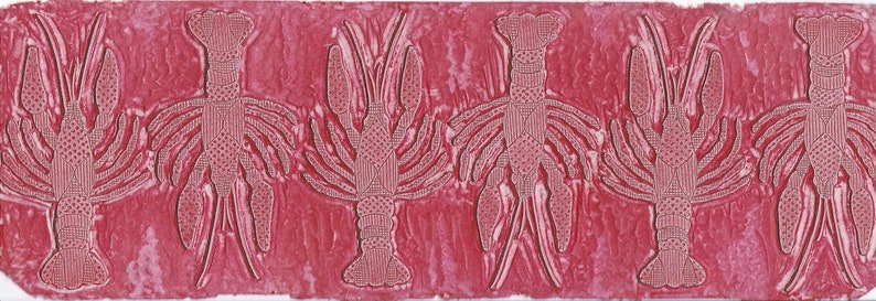 This is the hand carved block that was used to print or stamp the crawfish/lobster pattern on paper and textiles. The block is red ink stained from previous use.