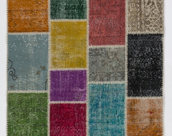 Puede incluir: Una alfombra de patchwork con una variedad de colores y patrones, incluyendo verde, azul, rojo, morado y amarillo. La alfombra está hecha de diferentes piezas de tela que se han cosido juntas.