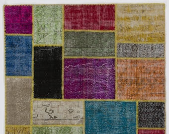 Puede incluir: Una alfombra de patchwork colorida con una variedad de patrones y colores, incluyendo rojo, azul, verde, amarillo y morado. La alfombra está hecha de materiales reciclados y tiene un aspecto único y hecho a mano.