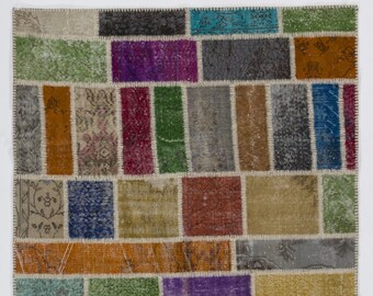 Puede incluir: Una alfombra de patchwork colorida con una variedad de colores y patrones, incluyendo verde, azul, rojo, naranja y morado. La alfombra está hecha de materiales reciclados y tiene un aspecto único y hecho a mano.