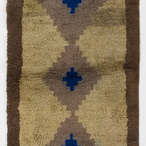May include: A vintage rug with a brown border and a beige background. The rug features three blue and gray diamond shapes with a blue cross in the center of each diamond.
