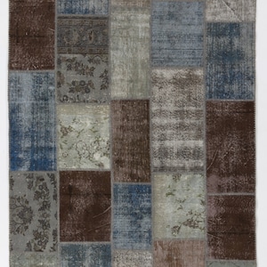 May include: A patchwork rug with a variety of colors and patterns, including blue, brown, and gray. The rug is made up of many different squares, each with a unique design.