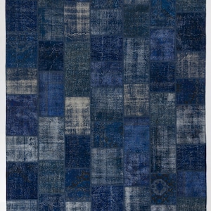 Könnte beinhalten: Ein Patchwork-Teppich in blau-weißer Farbgebung. Der Teppich besteht aus verschiedenen Stoffstücken, die zusammengenäht wurden, um ein einzigartiges Design zu schaffen.