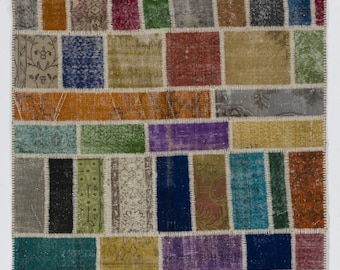 Puede incluir: Una alfombra de patchwork colorida con una variedad de colores y patrones, incluyendo verde, azul, rojo, naranja y marrón. La alfombra está hecha de materiales reciclados y tiene un aspecto único y hecho a mano.