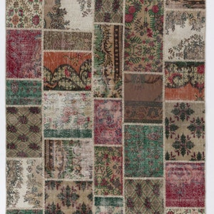 Könnte beinhalten: Ein Patchwork-Teppich mit einer Vielzahl von Farben und Mustern, darunter Rot, Grün, Braun und Beige. Der Teppich besteht aus vielen verschiedenen Stoffquadraten, die jeweils ein eigenes einzigartiges Design haben.