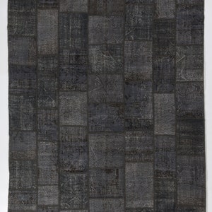 May include: A patchwork rug with a geometric pattern in shades of gray. The rug is made of different pieces of fabric sewn together.