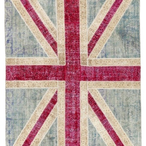 Puede incluir: Una alfombra rectangular con el diseño de la bandera de la Union Jack. La alfombra tiene un fondo azul claro con un diseño de patchwork. La cruz de la bandera es de color rojo intenso, con detalles en blanco roto y rojo. Un artículo de decoración del hogar.