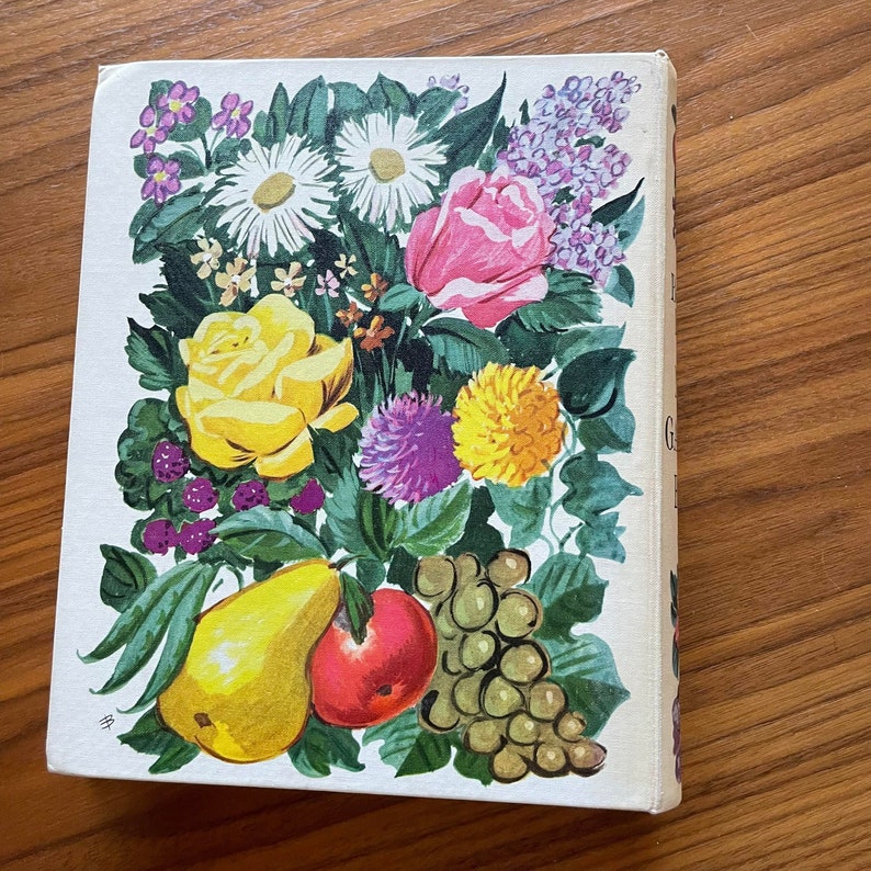 May include: A vintage book cover with a colorful illustration of flowers, fruits, and a pear. The flowers are pink, yellow, white, and purple. The fruits are red, green, and yellow.