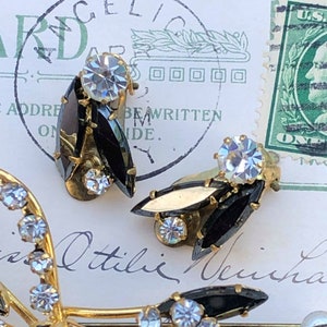 Puede incluir: Un par de pendientes vintage de clip con piedras negras en forma de marquesa y brillantes transparentes. Los pendientes son de color dorado y tienen un dise&ntilde;o cl&aacute;sico.