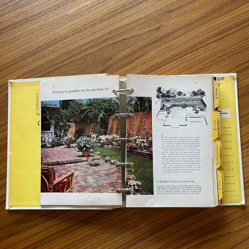May include: Open book with yellow tabs showing different sections. The book is about gardening and features a photo of a brick patio with a small garden and a fence. The text on the page reads "Privacy is possible on the smallest lot".
