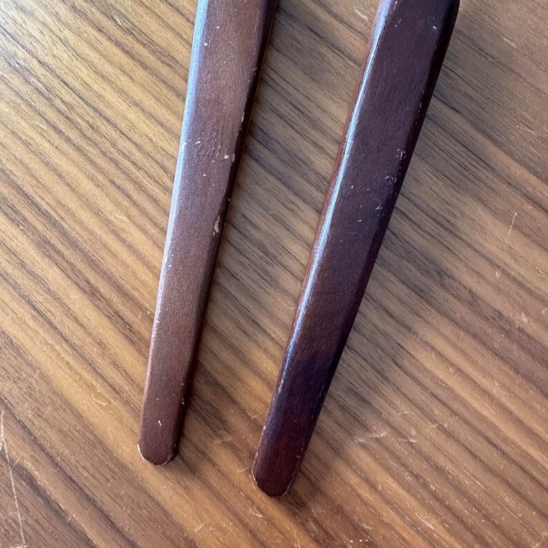 May include: Two wooden handles with a dark brown finish. The handles are smooth and have a slightly rounded shape.