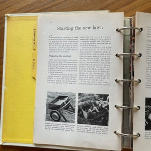 May include: A close-up of a page from a book about lawn care. The page features a black and white photo of a hand-operated lawn roller. The text on the page discusses preparing the seedbed for a new lawn, including the use of topsoil, fertilizer, and limestone.