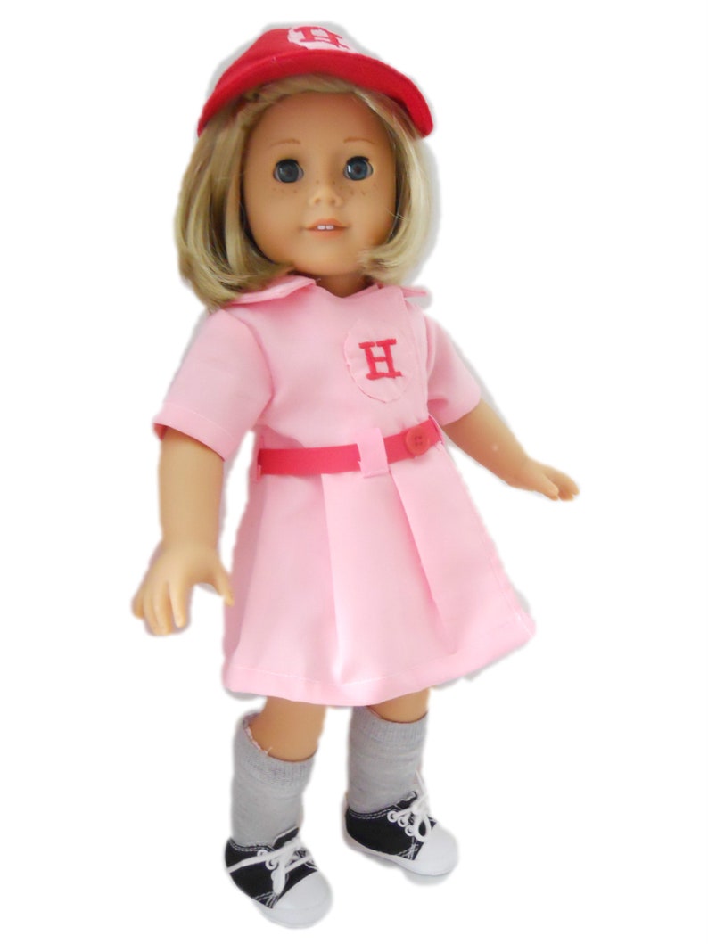 May include: A pink baseball uniform with a red belt and a red cap with a white "H" on it. The doll is wearing grey socks and black sneakers.