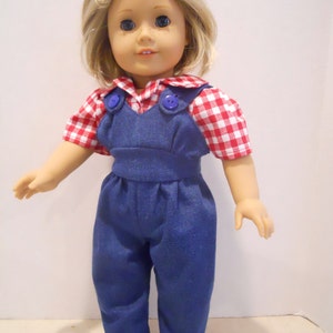 Puede incluir: Una mu&ntilde;eca con una camisa de cuadros rojos y blancos con un mono vaquero azul y zapatos blancos.