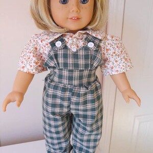 Puede incluir: Una mu&ntilde;eca con un vestido de peto de cuadros verdes y blancos con una camisa de estampado floral. La mu&ntilde;eca tiene el pelo rubio y los ojos azules.