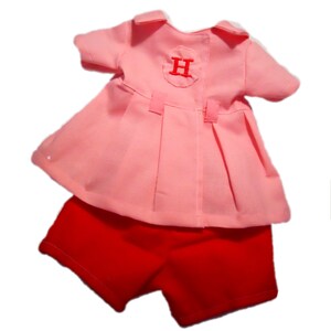 May include: A pink dress with a white circle and the letter "H" embroidered on the back, paired with red shorts.