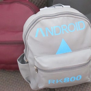 May include: Gray backpack with the word "ANDROID" and a blue triangle with a dotted pattern. The backpack also has the text "RK800" in blue.