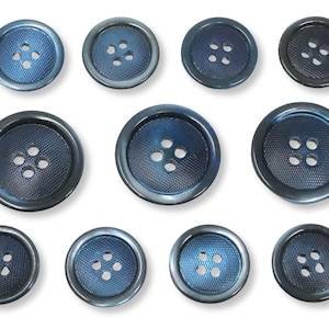 以下が含まれることがあります： さまざまなサイズのネイビーブルーのボタンのコレクション。各ボタンには4つの穴とテクスチャ加工された中央部があります。ボタンはメタリックな光沢があり、青色のグラデーションになっています。ボタンは白い背景に配置されています。