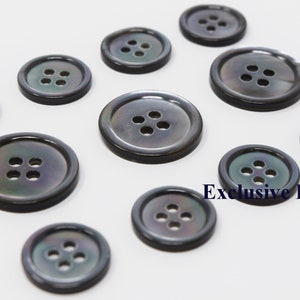 Puede incluir: Un conjunto de diez botones de nácar negro, cada uno con cuatro agujeros. Los botones están dispuestos en círculo sobre un fondo blanco. El texto "Exclusive Buttons" es visible en la esquina inferior derecha de la imagen.