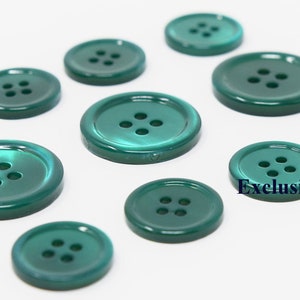 Pode incluir: Um conjunto de dez botões de plástico verde, cada um com quatro furos. Os botões estão dispostos em uma fileira sobre uma superfície branca. O texto "Exclusive Buttons" é visível no canto inferior direito da imagem.