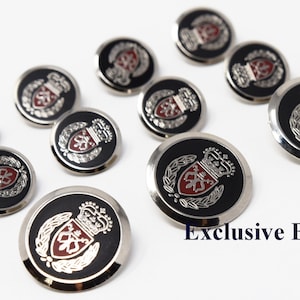 May include: A set of ten silver-toned buttons with a black background and a red and silver crest featuring a crown and a shield. The buttons are round and have a raised edge. The text "Exclusive Buttons" is visible in the bottom right corner of the image.