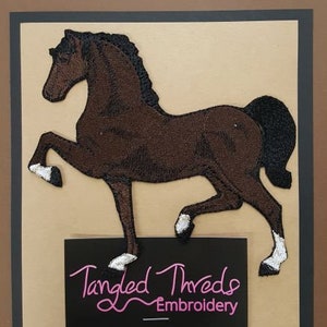 May include: Embroidered brown horse patch with white hooves, standing on its hind legs. The patch is on a beige background with a black rectangle below it that says "Tangled Threads Embroidery".