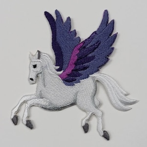 Peut inclure: Pégase brodé blanc avec des ailes violettes et roses. Le pégase est en plein vol, les ailes déployées.
