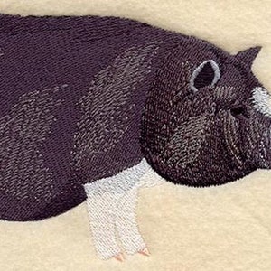 Puede incluir: Imagen bordada de un cerdo negro y blanco con una mancha blanca en la cara. El cerdo está de pie sobre sus cuatro patas y tiene una cola rizada.