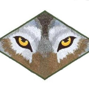 May include: Close-up of a wolf's face with piercing yellow eyes. The wolf's fur is a mix of gray and brown, and the image is in a diamond shape.