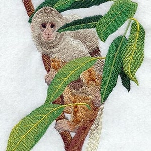 May include: Embroidered image of a monkey on a tree branch with green leaves. The monkey has light brown and tan fur, with a detailed facial expression. The leaves are a vibrant green, and the tree branch is brown.