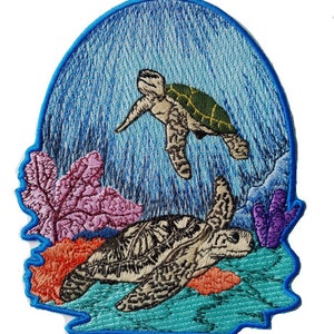 以下が含まれることがあります： 青い海のシーンで泳ぐ2匹のウミガメが刺繍されたパッチ。大きなウミガメはサンゴ礁のある海底で休んでおり、小さなウミガメは上を泳いでいます。パッチは青い縁取りをしています。