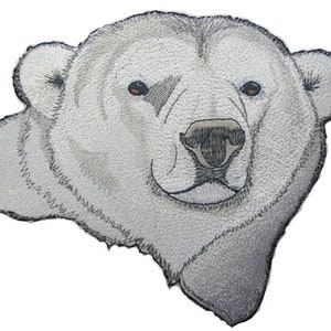 Puede incluir: Primer plano de la cara de un oso polar blanco. El oso tiene la nariz negra y los ojos marrones. La imagen es un bordado detallado.