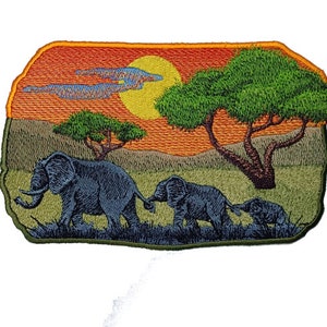 May include: Embroidered patch featuring a family of elephants walking across a savanna landscape. The design includes a sunset with a yellow sun, orange sky, and green trees. The elephants are gray and the grass is green.