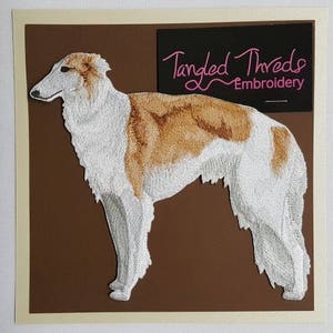 May include: Embroidered patch of a white and brown Borzoi dog with the text "Tangled Threads Embroidery" in a black rectangle.