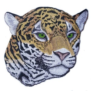 May include: Close-up of an embroidered patch depicting a jaguar's head. The jaguar has a brown and black spotted coat, green eyes, and a white muzzle.