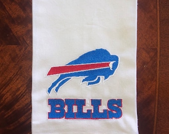 May include: White kitchen towel with an embroidered blue and red Buffalo Bills logo and the word "BILLS" in blue and red lettering.