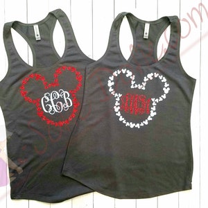 Könnte beinhalten: Zwei graue Tanktops mit einem Mickey-Mouse-Kopf-Design. Ein Tanktop hat einen roten Glitzer-Mickey-Mouse-Kopf mit dem Monogramm "CGB" in der Mitte. Das andere Tanktop hat einen weißen Glitzer-Mickey-Mouse-Kopf mit dem Monogramm "MOM" in der Mitte.