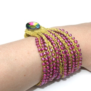 Könnte beinhalten: Ein mehrreihiges Armband mit rosa und goldenen Perlen und einem bunten Strassknopfverschluss.