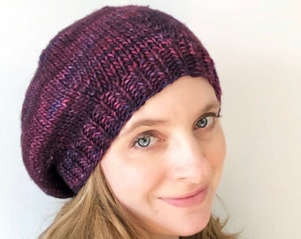 May include: A purple and pink knitted beanie with a slouchy fit.
