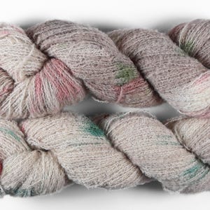 May include: Close-up of a skein of yarn with a textured appearance. The yarn is a blend of colors, including cream, pink, green, and brown. The yarn is tightly twisted, creating a thick, rope-like structure. The yarn is likely used for knitting or crocheting.