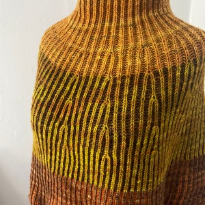 May include: A knitted cowl with a high neck and a striped pattern in shades of brown, orange, and yellow.