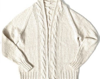 May include: A cream knitted cardigan with a cable knit pattern and a shawl collar.