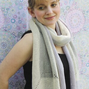 May include: A woman wearing a white and lavender striped scarf with a delicate knit pattern. The scarf is draped around her neck and shoulders.