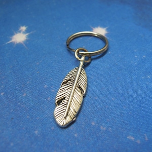 May include: A silver feather keyring with a silver key ring. The feather is detailed and has a realistic look.