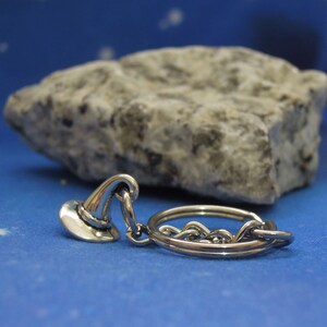 May include: A silver keychain with a small, detailed wizard hat charm. The charm is attached to a silver key ring.