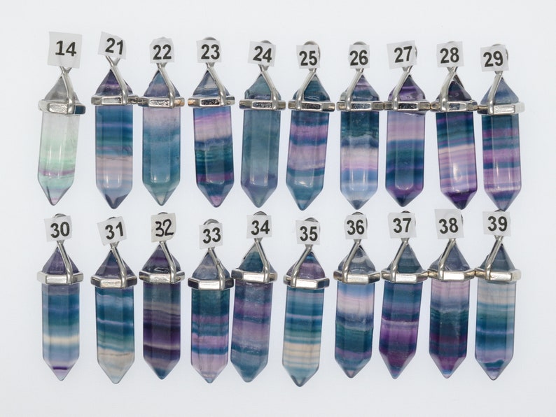 Puede incluir: Un conjunto de 16 colgantes de cristal de fluorita con una anilla de metal plateada. Los cristales son todos de diferentes tonos de azul, morado y verde. Los colgantes est&aacute;n numerados del 14 al 39.