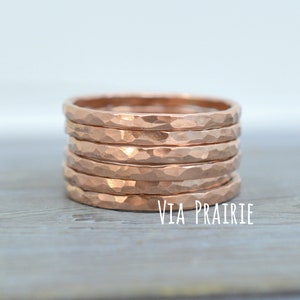 May include: A stack of six hammered copper rings. Each ring has a textured, faceted surface. The rings are stacked on a light grey surface. The text "VIA PRAIRIE" is visible in white.