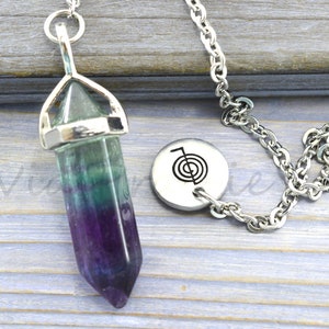 May include: A silver chain with a green, purple and blue fluorite crystal pendulum and a silver charm with a symbol of a spiral.