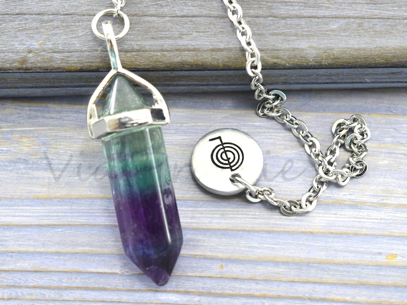 Puede incluir: Una cadena de plata con un p&eacute;ndulo de cristal de fluorita verde, morado y azul y un dije de plata con un s&iacute;mbolo de espiral.